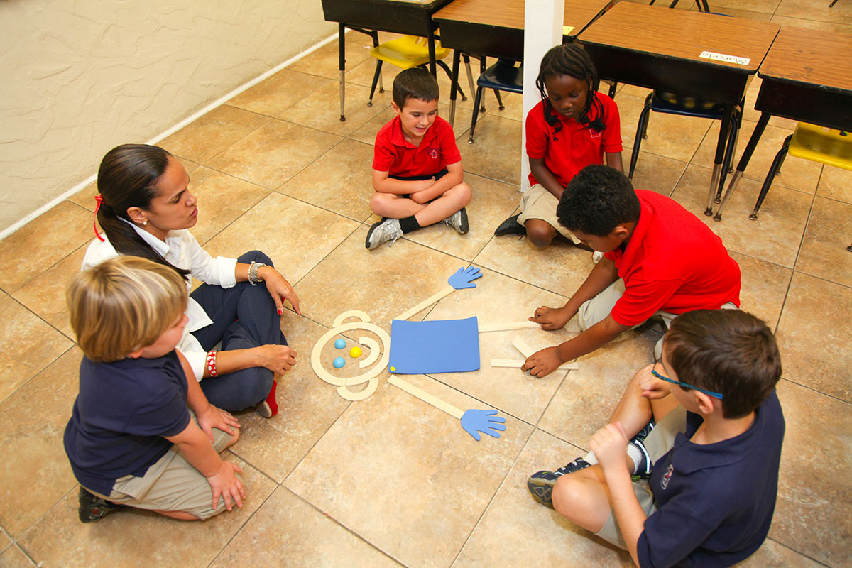kids and a teacher sitting on the floor with a paper cutout